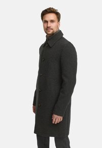 Dunkelgrauer Wollmantel mit hohem Kragen, Knopfverschluss und seitlichen Taschen. Verfügt über ein strukturiertes Design und eine glatte Textur.