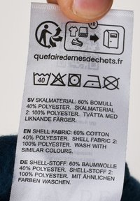 Etichetta di cura con composizione del tessuto: 60% cotone, 40% poliestere e 100% poliestere. Include istruzioni per la cura e simbolo di riciclaggio.