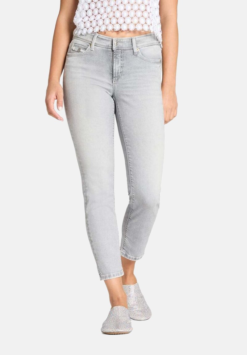 Lichtgrijze denim jeans met een slanke pasvorm, een middelhoog silhouet en een cropped lengte. Zichtbare voorzakken en afgewerkte zoom; gestyled met een wit topje.