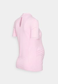 Top de maternidade em rosa claro com textura canelada, mangas curtas, gola alta, abertura em forma de buraco nas costas e franzidos laterais para ajustar e proporcionar conforto.