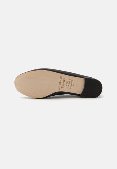 Svart platt sko med en slät textilövre och en ljusbeige lädersula. Innehåller präglade detaljer och en lätt gummihäl för bra grepp.