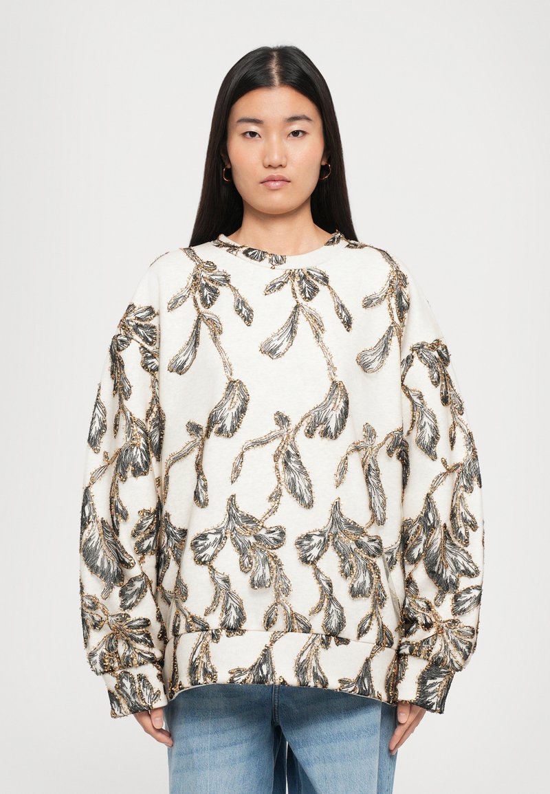 Oversized sweatshirt in off-white with black and gold floral embroidery. Features a round neckline and loose-fitting sleeves.