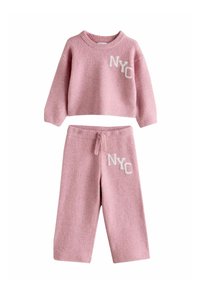 Zweiteiliges Set in Pink aus Strick mit einem cropped Sweater und passenden Hosen. Beide Teile haben "NYC" in Weiß gestickt und besitzen eine weiche Textur.