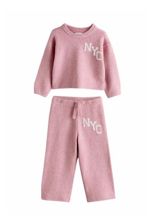Zweiteiliges Set in Pink aus Strick mit einem cropped Sweater und passenden Hosen. Beide Teile haben "NYC" in Weiß gestickt und besitzen eine weiche Textur.