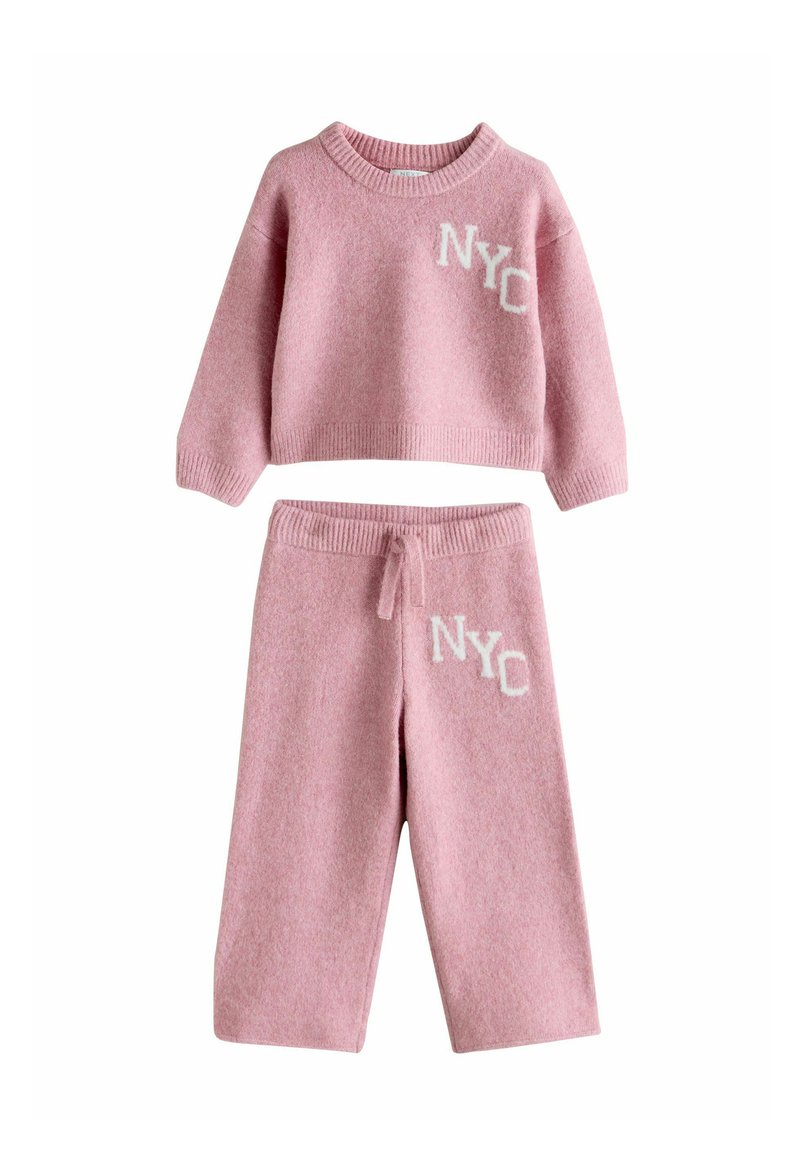 Zweiteiliges Set in Pink aus Strick mit einem cropped Sweater und passenden Hosen. Beide Teile haben "NYC" in Weiß gestickt und besitzen eine weiche Textur.