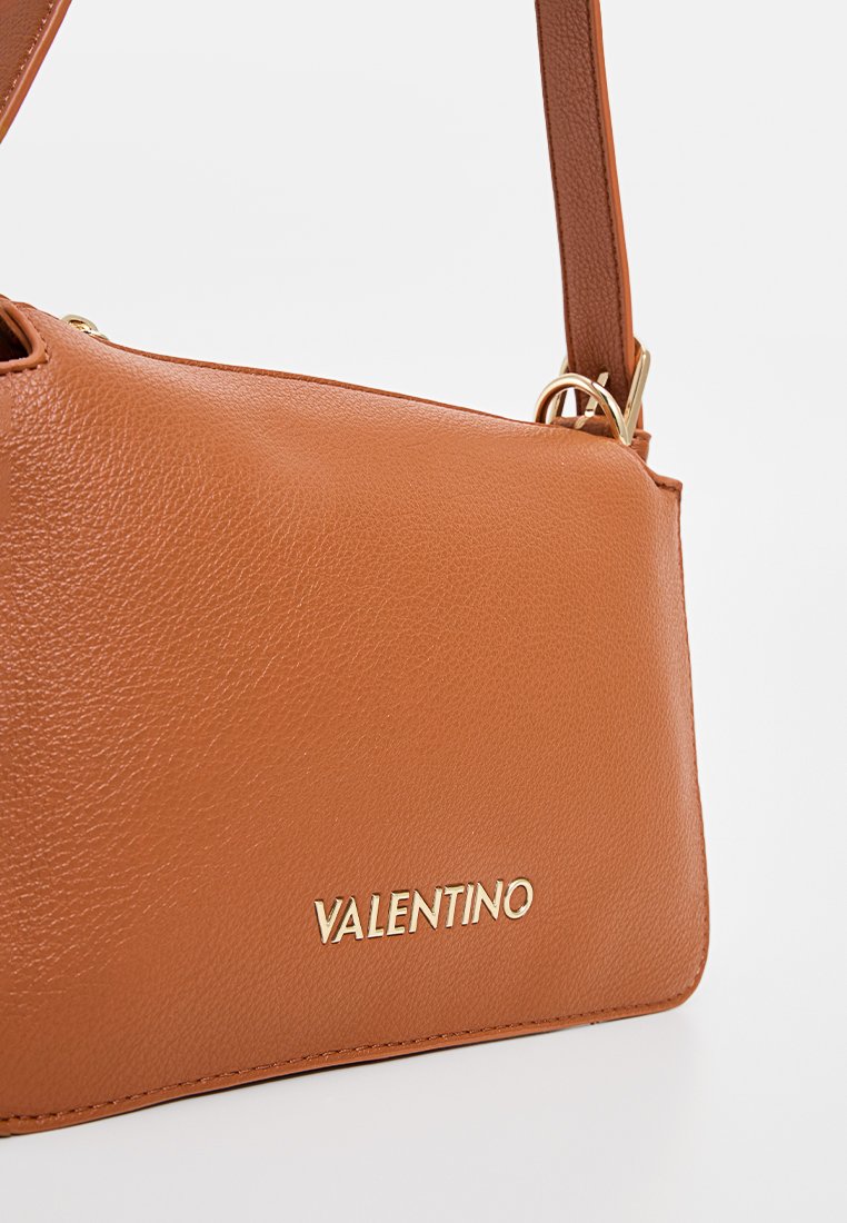Sac à bandoulière en cuir tan de Valentino avec logo doré et attaches de bandoulière sur un fond blanc.