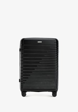 Schwarzer Hartschalenkoffer mit parallelen Rillen, zwei Rädern, einem oberen Griff und einer markierten Akzentplatte. Glatte Textur und rechteckige Form.