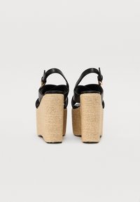 Svarte lær plattform sandaler med tykke vevde jute hæler og justerbare ankelstropper, med en glatt tekstur og minimalt utstyr.