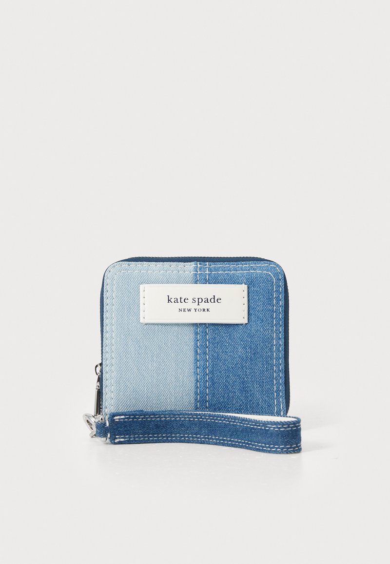 Denim wallet with a two-tone blue design, featuring a white label with "kate spade new york," zipper closure, and a detachable wrist strap.