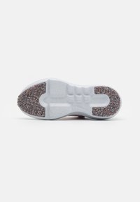Suela de zapato de goma gris texturizada, con un acento colorido moteado en el área del talón. Forma ergonómica con patrones de banda de rodadura distintivos.