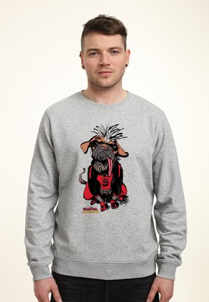 Man draagt een grijze trui met een afbeelding van een hond verkleed als Deadpool, die zijn tong uitsteekt en vooruit kijkt.