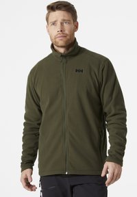 Giacca in pile di colore verde oliva scuro con colletto alto, zip frontale e logo sul lato sinistro del petto. Tessuto morbido, due tasche laterali.
