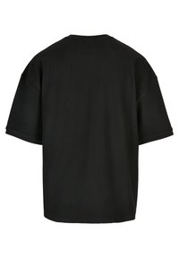 Tricou negru, supradimensionat, cu mânecă scurtă, textură canelată, decolteu larg și croială lejeră, prezentat din spate, fără logo-uri sau accente vizibile.
