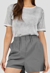 Szary prążkowany t-shirt z białymi wykończeniami, zestawiony z szarymi szortami o wysokim stanie z elastycznym pasem i bocznymi kieszeniami.