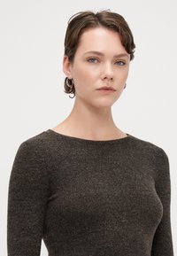 Barna bordás kötött pulóver, kerek nyakkivágással és hosszú ujjal, puha tapintással és testhez álló kialakítással.