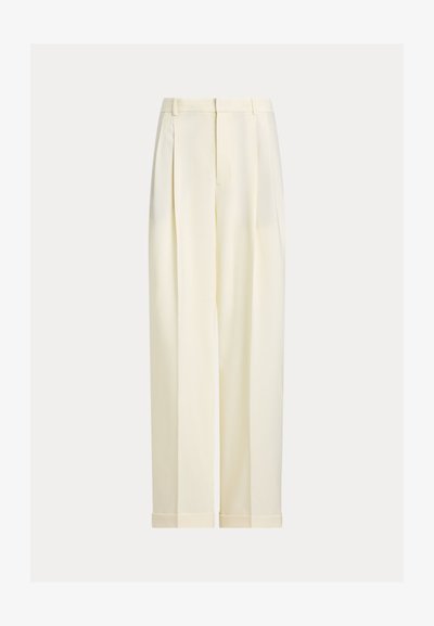 Παντελόνια σε εκρού χρώμα με πιέτες μπροστά, θηλιές για ζώνη και γυρισμένα τελειώματα, εκτεθειμένα σε απλό φόντο.