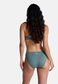 Ensemble bikini vert avec un design simple, bretelles ajustables, taille haute, et un petit logo au dos.