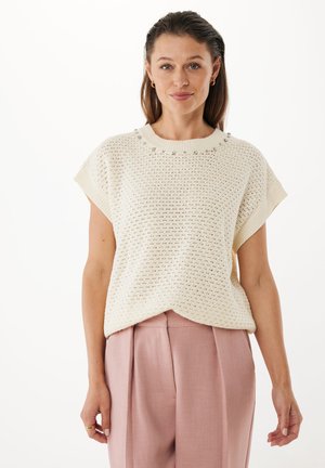 Pull en tricot crème clair à manches courtes, avec un motif texturé et des perles décoratives autour du cou. Assorti avec un pantalon rose.