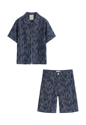 Chemise zippée à manches courtes bleu foncé à motifs et short assorti longueur genou posés à plat sur fond blanc.