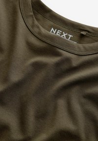 Khakifarbene T-Shirt mit Rundhalsausschnitt, aus glattem Baumwollstoff gefertigt, mit subtiler Textur und einem Etikett mit "NEXT" innen am Kragen.