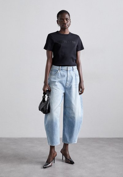 Μαύρο κοντομάνικο μπλουζάκι με ανάγλυφο λογότυπο, ανοιχτό μπλε ψηλόμεσα φαρδιά τζιν, μαύρη τσάντα και γυαλιστερές μυτερές γόβες.