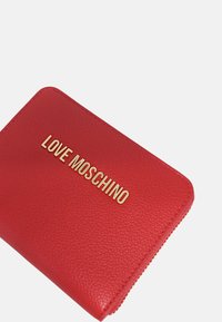 Red synthetic leather wallet with a textured finish, featuring gold "LOVE MOSCHINO" lettering on the front and a zip closure.