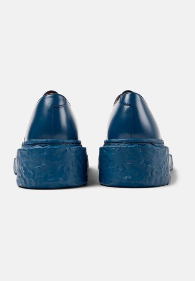 Blue leather shoes with a thick textured sole, featuring a sleek design and rounded back. Smooth finish with stitching detail.