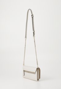 Sac bandoulière gris clair avec rabat pliable, quincaillerie dorée, poche zippée et bandoulière chaîne ajustable. Matériau texturé avec une finition lisse.