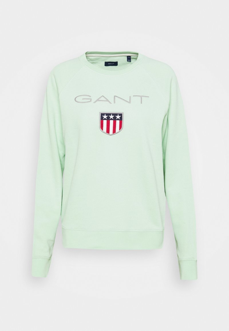 Sweat-shirt vert clair à col rond avec le texte "GANT" et un logo en forme de bouclier comportant trois étoiles ainsi que des rayures rouges et blanches sur la poitrine.