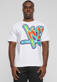 Hvit bomulls t-skjorte med en fargerik, abstrakt graffiti-stil design i rødt, grønt, blått og lilla på forsiden. Korte ermer.