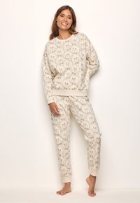 Conjunto de sudadera y pantalones en color beige con un estampado repetido de cara de oso marrón claro. Tela suave, detalles de puños y cintura acanalados.