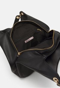 Svart läderhandväska med texturerad yta, guldfärgad dragkedja och ringar. Inuti finns en fack med dragkedja och ett tygfodral.