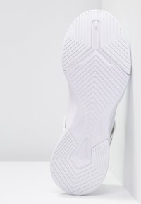 Bílá podrážka tenisky s texturovanou gumou, se geometrickým vzorem, hladkými okraji a mírným zakřivením v oblasti paty pro větší stabilitu.