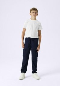 Witte short-sleeve t-shirt gecombineerd met marineblauwe cargo-broek met zijzakken en witte sneakers met een dikke zool.