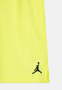 Helle gelbe Shorts aus glattem Material mit einem schwarzen gestickten Jumpman-Logo am unteren Saum. Verfügt über seitliche Schlitzdetails.