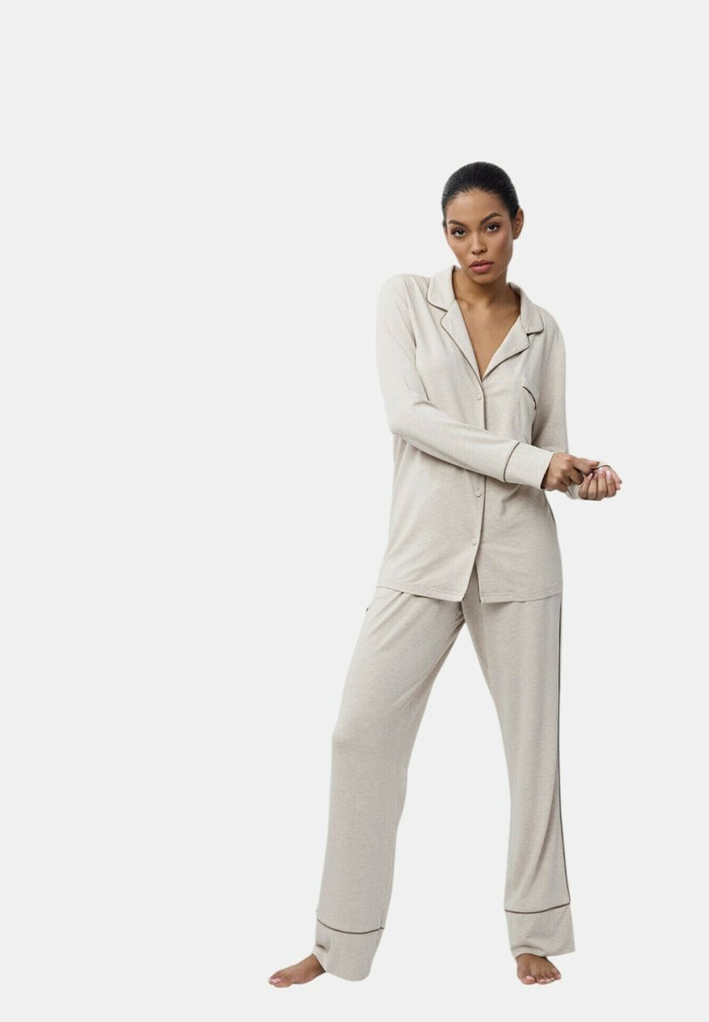 Ensemble de pyjama beige en tissu doux, doté de manches longues, d'un haut à boutons et d'un pantalon ample avec des ourlets à revers, offrant une coupe décontractée.