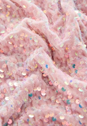Tissu rose avec une surface texturée, orné de sequins irisés. Texture douce et moelleuse avec un aspect légèrement froissé.