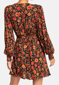 Robe florale noire ornée de fleurs rouges et jaunes, avec de longues manches bouffantes, une taille ceinturée et un ourlet froncé. Fabriquée en tissu léger.