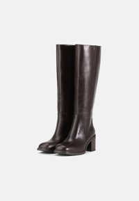 Barna bőr, térdig érő csizmák sima felülettel, tömb sarkú kialakítással, kiemelt varrási részletekkel és testhezálló sziluettel.