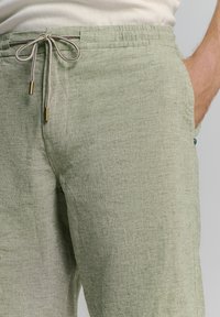 Linnenmix broek in zacht groen met een elastische tailleband. Voorzien van een trekkoordsluiting met gouden accenten en zijzakken. Geweven patroon.