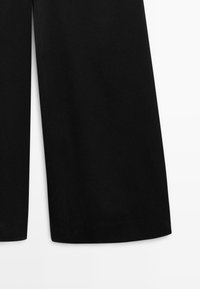 Zwarte wijde broek met een cropped lengte bij de enkels, weergegeven op een witte achtergrond, waarbij de onderste helft van elk broekspijp zichtbaar is.