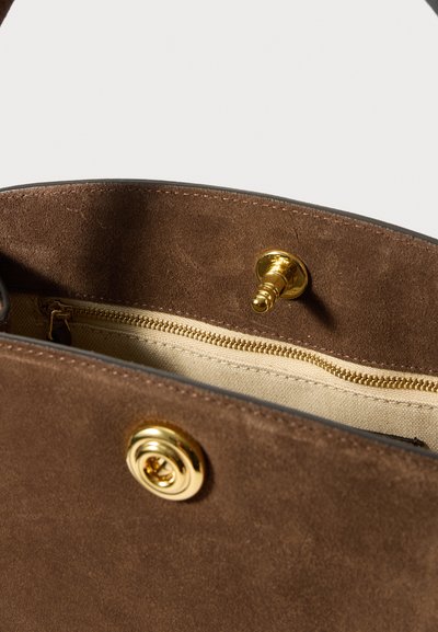 Εσωτερικό καφέ σουέντ τσάντας με μπεζ ύφασμα για επένδυση, χρυσό φερμουάρ και χρυσό μαγνητικό κούμπωμα.