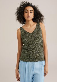 Green tank top with a v-neck and black leopard print, made from soft fabric; paired with light blue wide-leg pants.