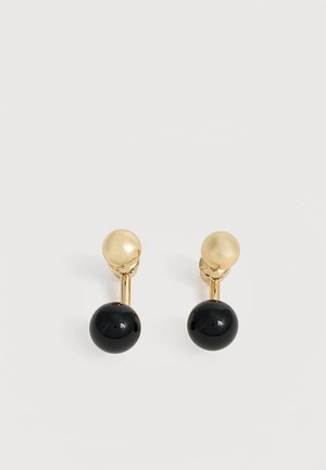 Boucles d’oreilles clous en or avec une barre courte reliant une perle sphérique noire brillante plus grande, présentées sur un fond blanc.