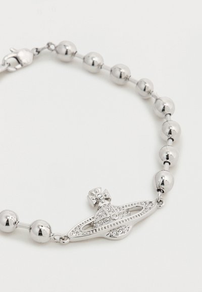 Armband met zilverkleurige kralen en een juweelvormig embleem in de vorm van een planeet met ringen en een kruis erop, tegen een effen witte achtergrond.