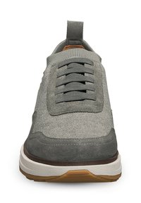 Sneaker grigio con una tomaia in tessuto testurizzato, lacci elastici, linguetta e suola in gomma a contrasto con accenti marroni.