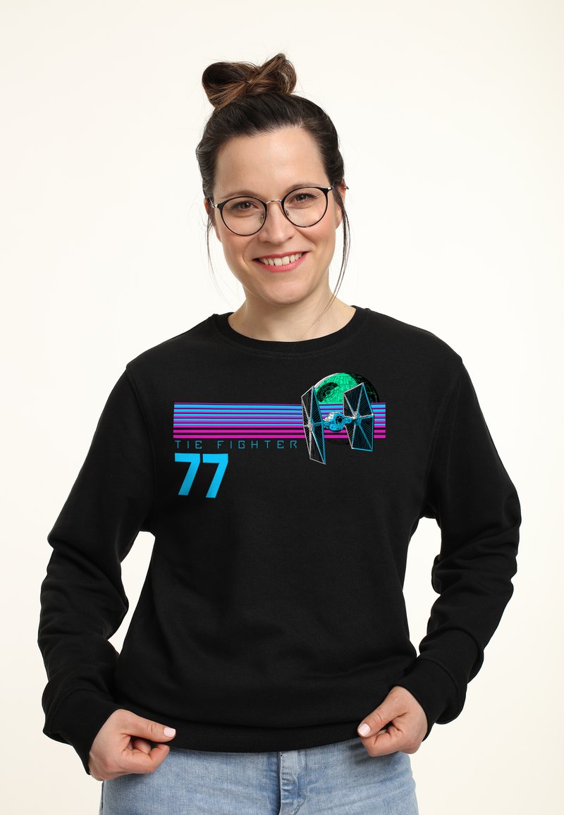 Sudadera negra con un gráfico de "TIE FIGHTER" en teal, rosa y azul, con rayas horizontales y el número "77" en el frente.
