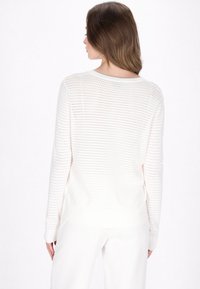 Maglione bianco a maglia con un design perforato, maniche lunghe, polsini e orlo a costine. La vista da dietro mostra un collo rotondo e una vestibilità ampia.