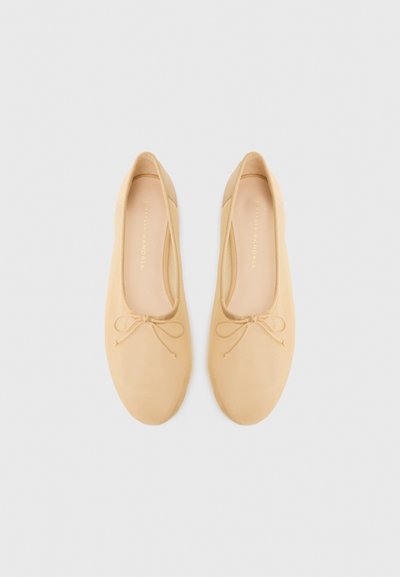 Beige ballet flats made of soft fabric, with a rounded toe and a small bow detail on each shoe. Smooth texture and minimalistic design.