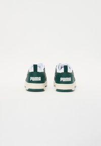 Zelene tenisice od umjetne kože s bijelim detaljima, s trakom za povlačenje, podstavljenim ovratnikom i "PUMA" logotipom na peti. Čvrst gumeni potplat.